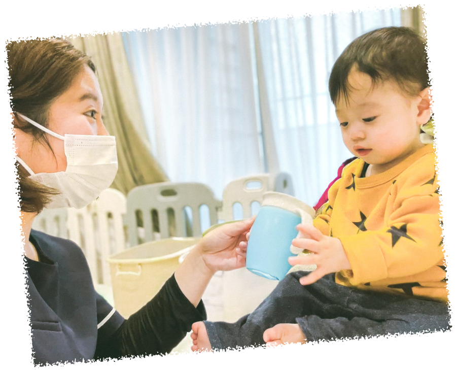 笑顔でコップを渡しているスタッフと子ども