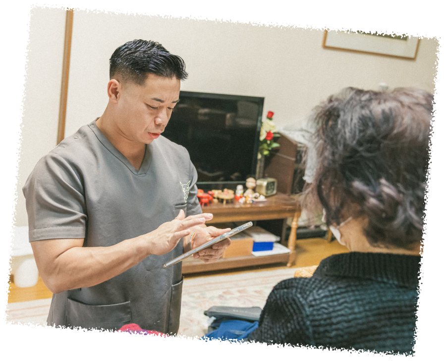 男性スタッフがタブレットを操作し、高齢女性と話している