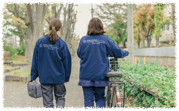 女性スタッフ二名が自転車を押しながら訪問看護に向かっている後ろ姿