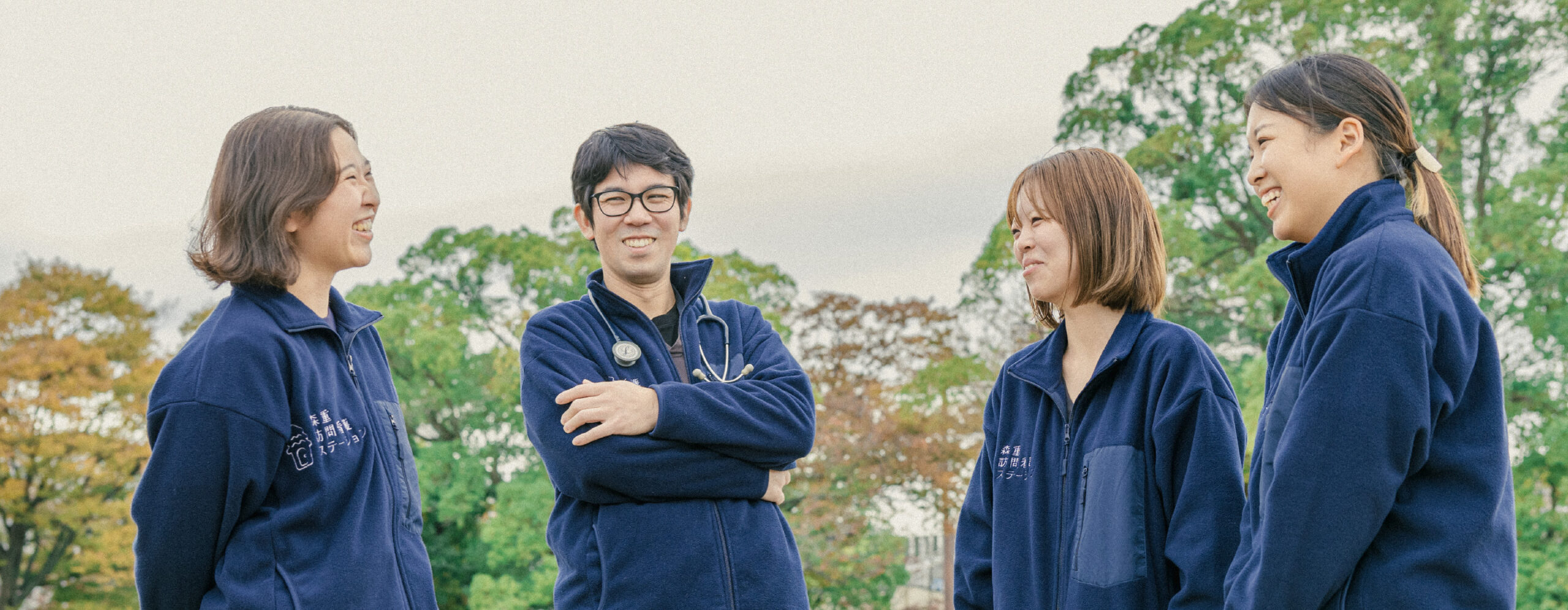 笑顔で縦会話する男性スタッフ1名と女性スタッフ3名