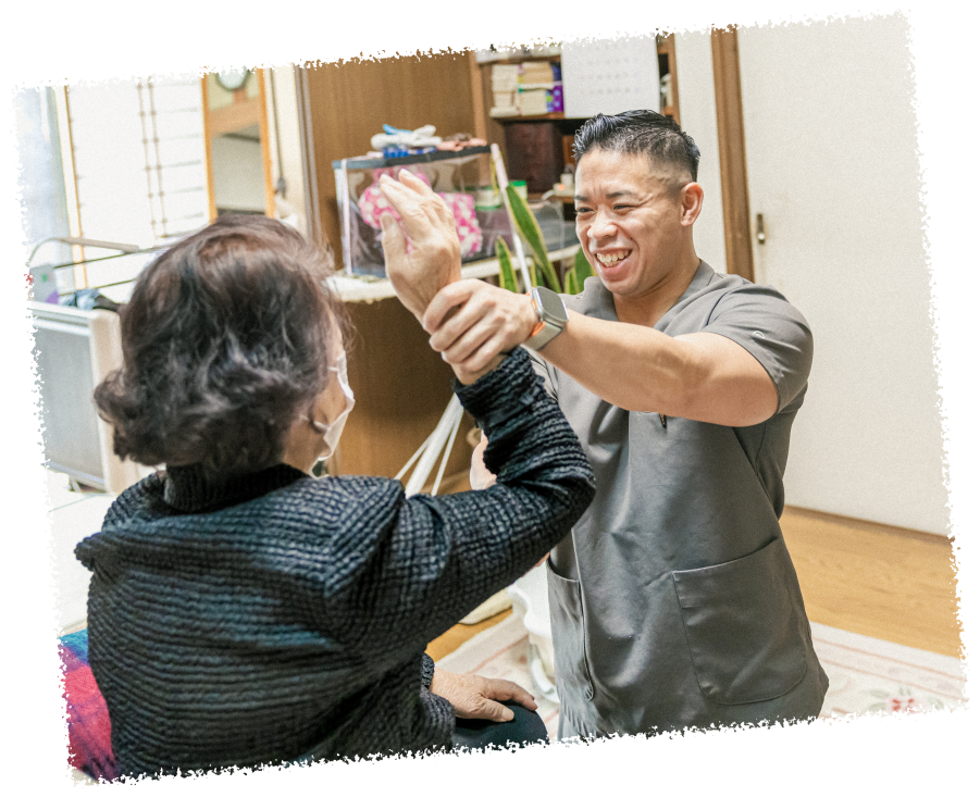 笑顔の男性スタッフが高齢女性の右上を上げてストレッチを行っている