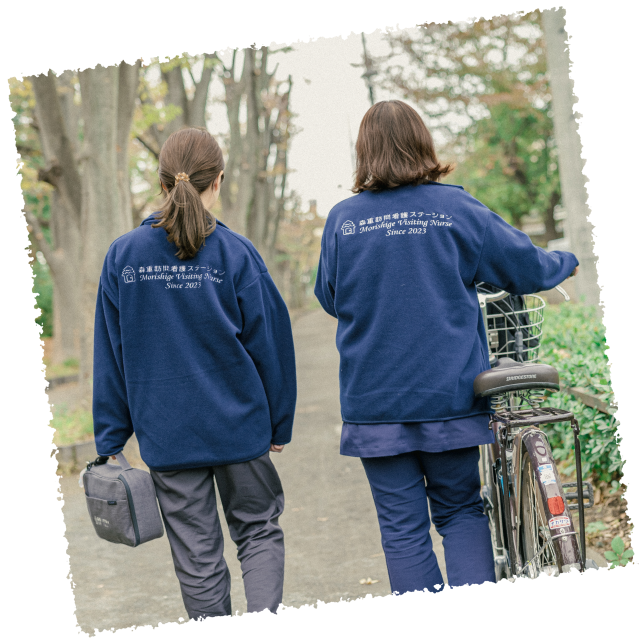 女性スタッフ二名が自転車を押しながら訪問看護に向かっている後ろ姿
