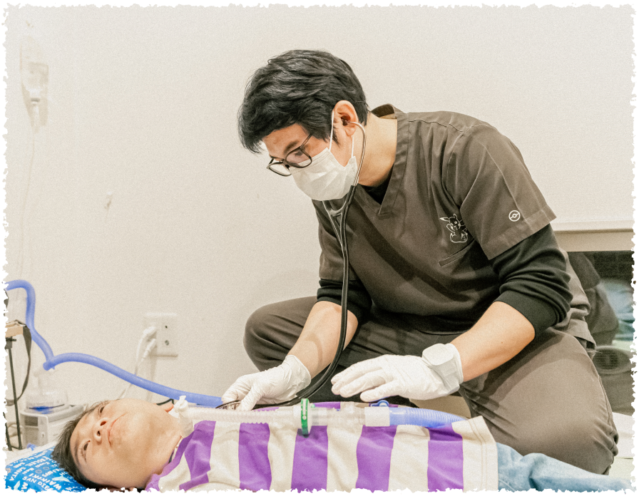 布団に寝ている男の子に聴診器を当てる男性スタッフ