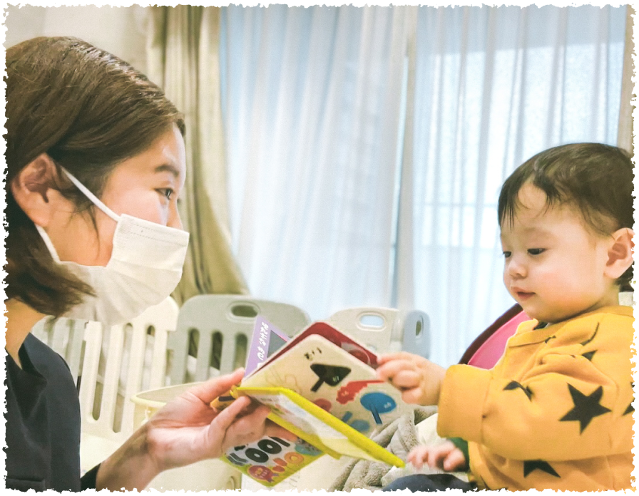 絵本を読んで遊んでいる笑顔のスタッフと子ども