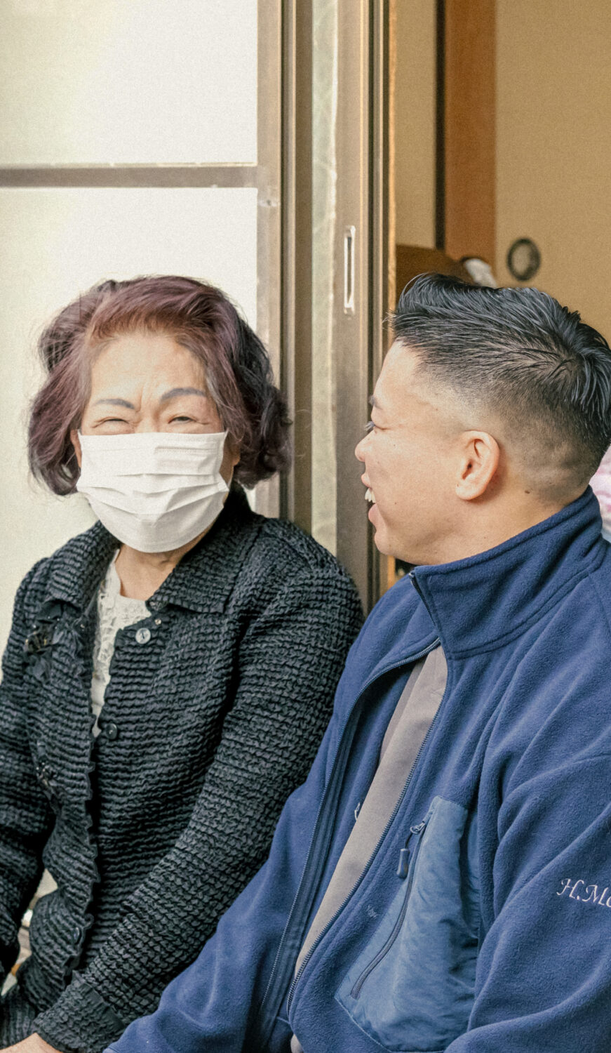 高齢女性と男性スタッフが縁側で談笑している